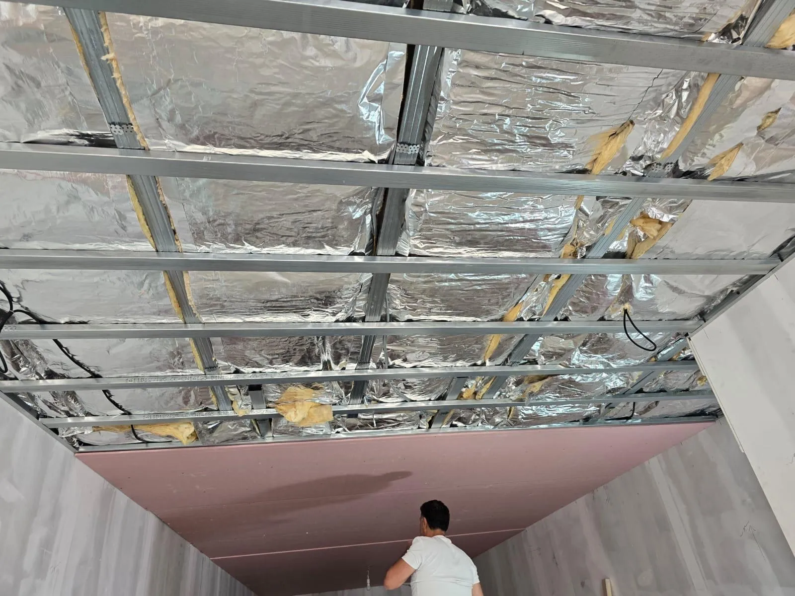 Montage van plafondisolatie met reflecterende folie en minerale wol